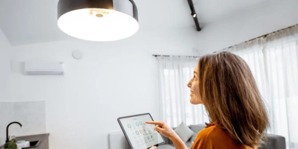 woman looking at hanging pendant light with an iPad in her hand controlling the wireless light switches